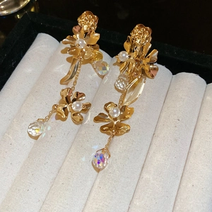 Detail of gold flower tassel earrings with pearls and iridescent crystal on velvet