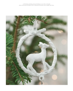 White reindeer resin ornament with snowy texture hanging on a decorated Christmas tree