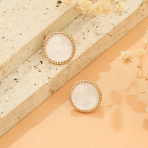 Detail of round marble studs with golden beaded edges on textured travertine stone