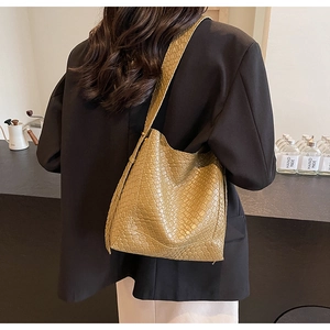 Khaki woven tote bag styled with a black blazer showing its large capacity and texture