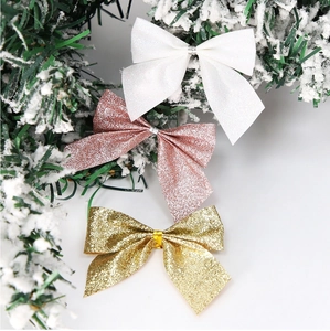 Glittery Christmas bows in white, gold, and pink on snow-covered pine branches