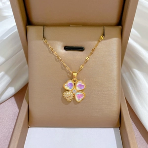 Vue rapprochée du pendentif trèfle doré avec pétales irisés et diamants en coffret cadeau