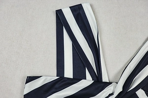 Macro detail of silky black and white striped fabric showing fine stitching on a V-neck dress
