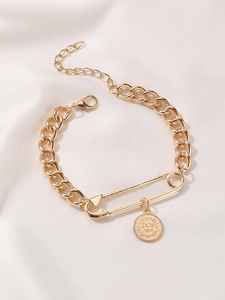 Detailed close-up of gold paperclip chain bracelet with coin pendant on white silk