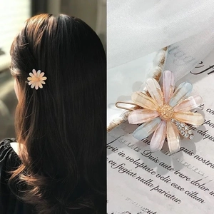 Detailed close-up and styling of a daisy hair clip with rhinestones and gradient petals