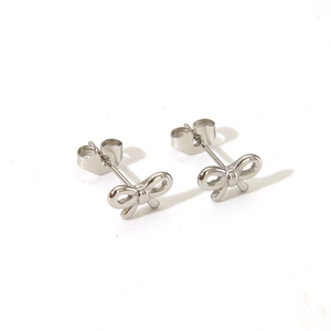 Detailed close-up of polished silver bow stud earrings with butterfly back fasteners