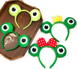Détail de quatre serre-têtes grenouille en peluche verte avec couronne et nœud à pois