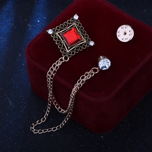 Detail of vintage gold brooch with square red gem and elegant tassel chains on velvet