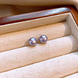 Macro shot of elegant lavender purple pearl stud earrings in a wooden jewelry box
