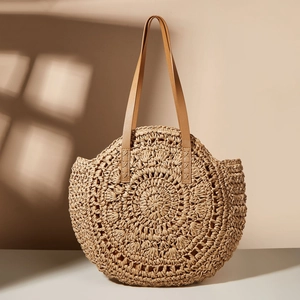 Detailed texture of circular woven straw tote bag with brown leather handles and stitching