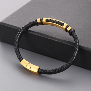 Detail of black braided leather bracelet featuring a gold metal bar and magnetic buckle