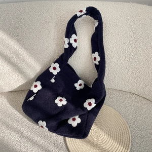 Dettaglio della borsa tote in maglia blu scuro con motivo floreale e dettagli rossi