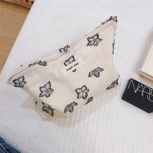 Detail of cream canvas makeup bag with black floral prints and a simple wish fabric tag