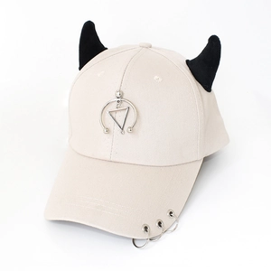 Close-up of cream baseball cap with black 3D devil horns and silver metal ring accents