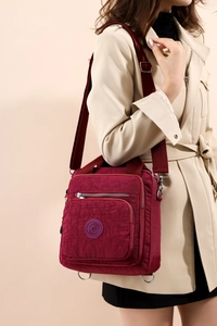 Vue détaillée du sac à langer bordeaux en nylon avec logo rond et multipoches
