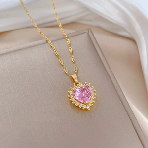 Detail of gold heart pendant with pink zircon and micro-pave crystals on white silk