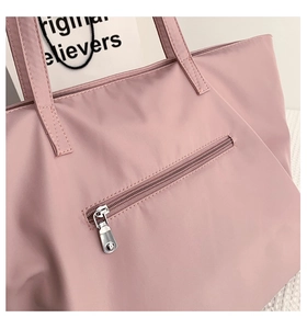 Detailed close-up of pink nylon tote bag with functional back zipper pocket and clean seams
