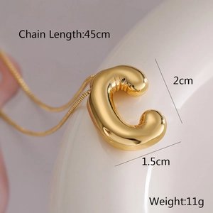 Macro shot of gold letter C balloon pendant with dimensions 2cm by 1.5cm on white surface
