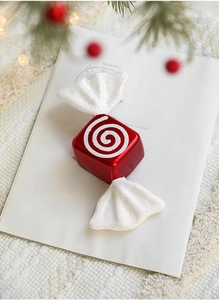 Close-up of red and white striped candy Christmas ornament on an elegant book background