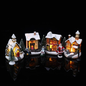Close-up of glowing LED Christmas village miniatures on reflective black surface