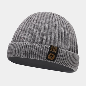 Détail de la texture en maille côtelée grise et de l'étiquette tissée du bonnet d'hiver