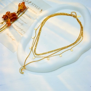 Layered gold titanium necklace with star charms and crescent moon pendant on white plate