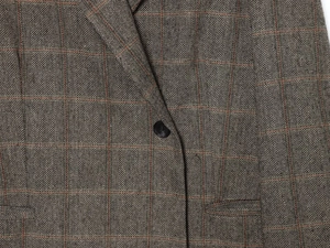 Detail of herringbone linen wool blazer with red plaid patterns and single black button