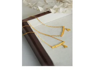 Gros plan détaillé d'un collier pendentif en bambou doré sur un présentoir en bois