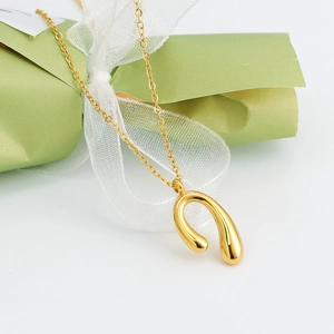 Minimalist gold U-shaped horseshoe pendant necklace with polished 18K gold finish