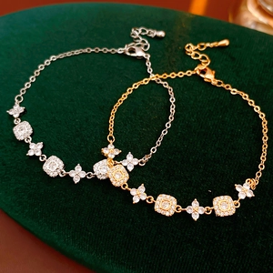 Close-up of gold and silver adjustable floral bracelets with zircon on dark green velvet