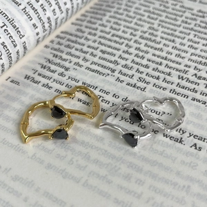 Detailed view of silver and gold heart earrings with black gems on an open book