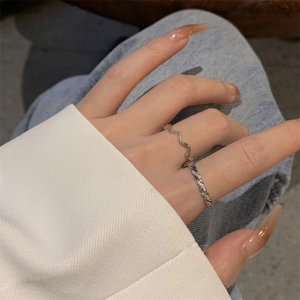 Detail of silver twisted pave ring and wavy band on hand with zircon accents