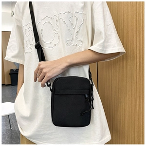 Model wearing a black canvas shoulder bag showing adjustable strap and size perspective