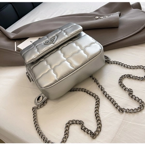 Close-up of silver quilted crossbody bag with heart buckle and metal chain strap