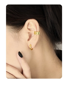 Close-up of minimalist gold S925 silver wave ear cuff and hoop earrings on model ear