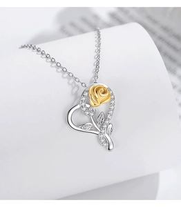 Macro shot of silver heart pendant featuring a 3D gold rose and white cubic zirconia