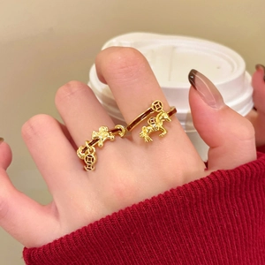 Detailed close-up of a gold-plated horse ring with red enamel and lucky coin charm