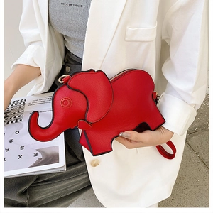 Detail of red elephant crossbody bag with gold zipper held by a model in a white blazer