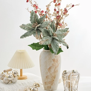 Poinsettia artificiel gris-vert avec paillettes dorées dans un vase en céramique vintage