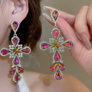 Macro shot of silver needle cross earrings with colorful rhinestones and gold plating