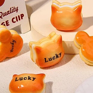 Close-up of orange cat-shaped resin clips featuring black Lucky text engraving