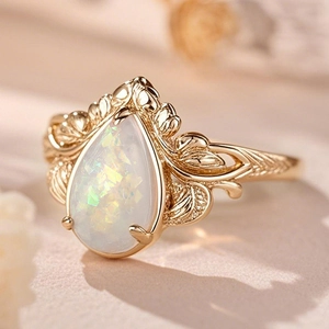 Macro shot of pear-shaped opal ring with intricate gold leaf textures and vintage details
