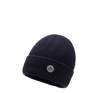 Dettaglio della cuffia in maglia blu scuro con trama a coste e toppa in pelle