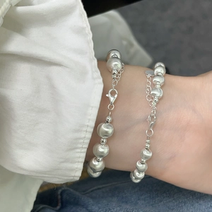 Detailed view of layered silver beaded bracelets with adjustable lobster clasp on wrist