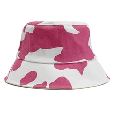 Detail shot of white bucket hat featuring vibrant magenta cow print patterns and round top