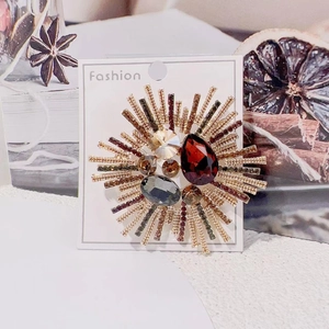 Detailed close-up of luxury sunflower brooch with red and smoky crystals on golden base