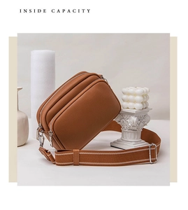 Detailed view of brown lychee leather shoulder bag with wide strap and triple zipper design