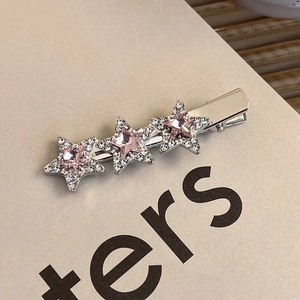 Macro detail of silver star hair clip with pink crystal and pavé rhinestones