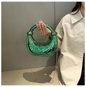Detail of green metallic acrylic handbag with diamond lattice pattern and gold chain