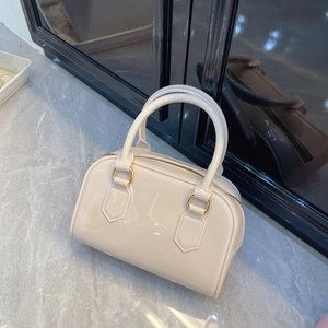 Detail of glossy beige Boston bag featuring golden hardware and top zipper closure
